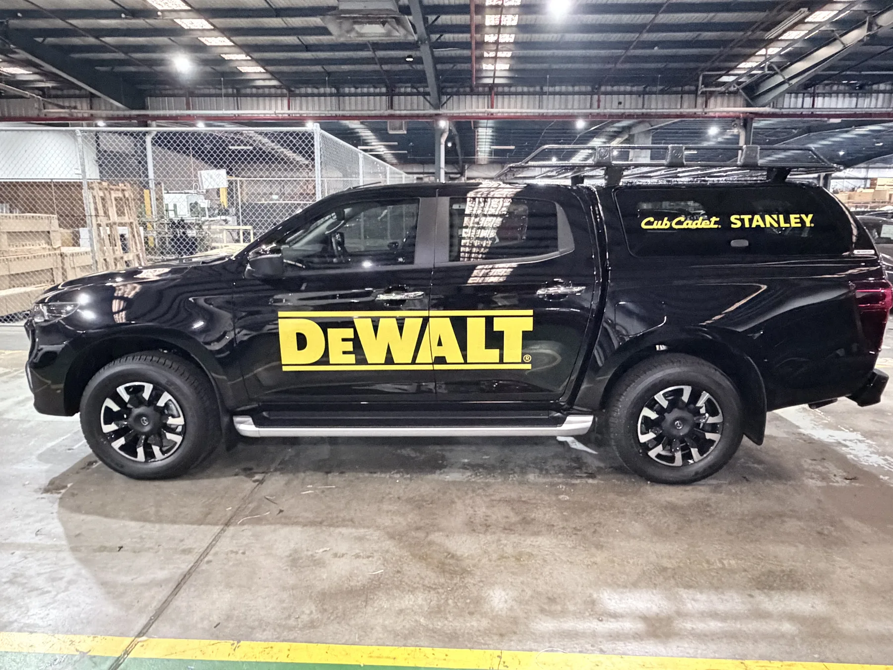 Side view of a DEWALT branded utility vehicle with Stanley and Cub Cadet graphics