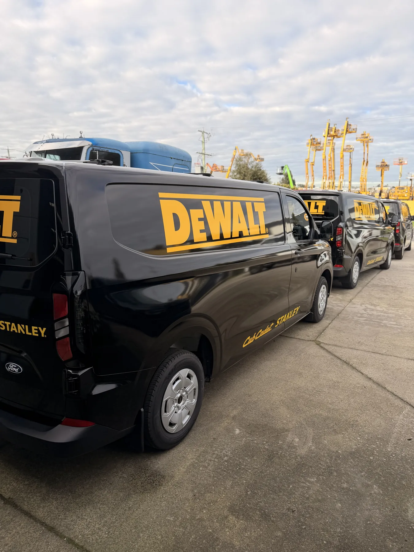 Line-up of commercial vans wrapped in gloss black with DEWALT fleet graphics